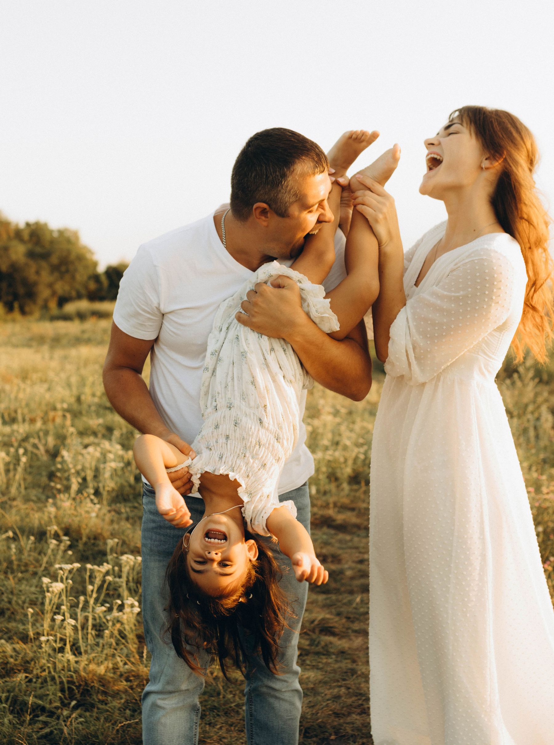 Des parents jouent et rient avec leur fille dans un champ